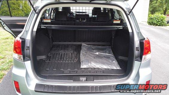 Rear view of a 2014 Subaru Outback cargo area with floor mats and a plastic-wrapped item