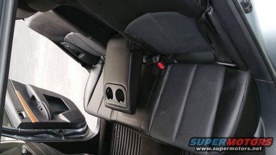 Rear seats and door panel of a car interior. Black leather seats with a center console and cup holders visible