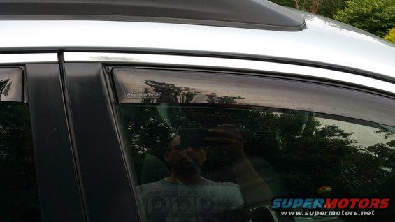 Side door window with WeatherTech visor and reflection of person holding phone