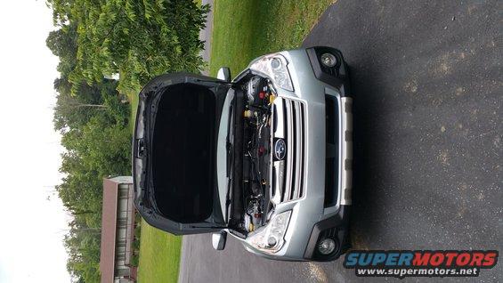 Silver Subaru Outback with hood open, parked on asphalt driveway