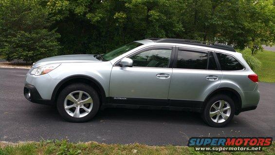 Silver Subaru Outback parked on asphalt, side view. "OUTBACK" text visible on lower door trim