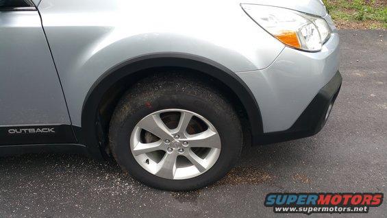 Silver 2014 Subaru Outback front wheel and fender with 'OUTBACK' badge on the lower door