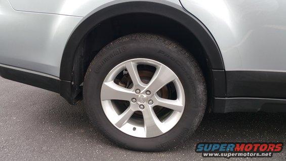 Silver Subaru Outback rear wheel and fender with black trim. Tire is Continental ProContact