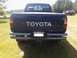 1993 Toyota Pickup/SR5 - A dark blue Toyota pickup truck is parked in a grassy area with another red vehicle in the background.