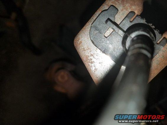 Close-up of rusty metal bracket with a black plastic piece and a metal rod