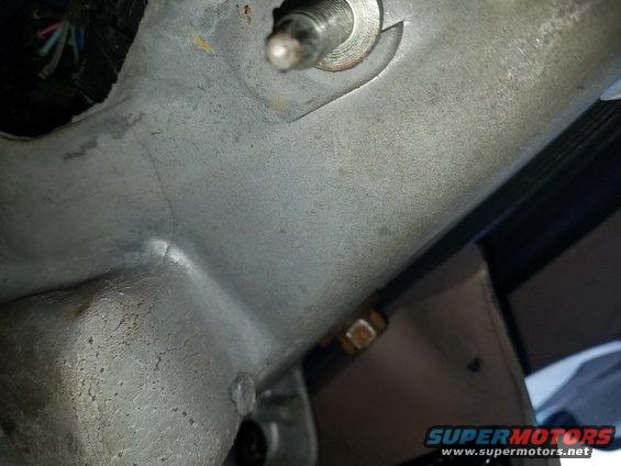 Close-up of a metal bracket with wires and a bolt in a vehicle's interior