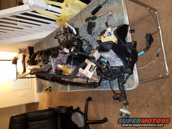 Disassembled dashboard wiring harness with various connectors and components spread out on a table
