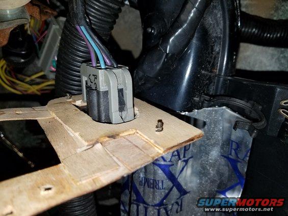 Wiring harness connector with purple, blue, and black wires attached to a wooden bracket