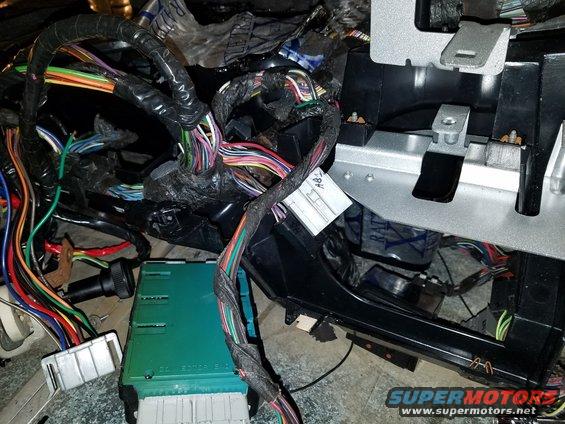 Close-up of a tangled vehicle wiring harness and a green electronic control module