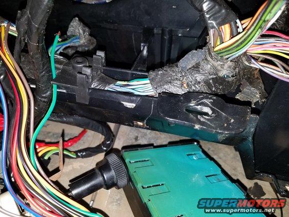 Close-up of a tangled vehicle wiring harness and a green electrical component