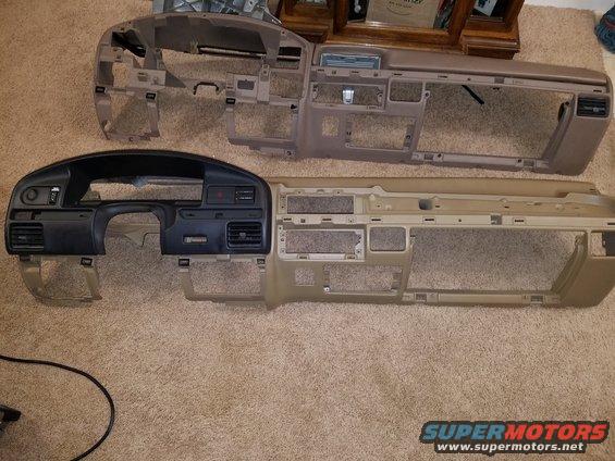 Two disassembled vehicle dashboards, one black and tan, one tan