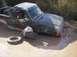 1989 Ford Bronco - A dark green pickup truck is stuck in muddy terrain, with one of its tires lying beside it.