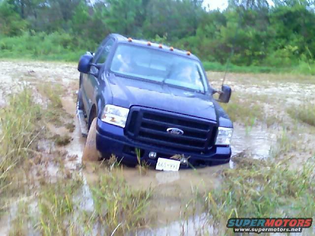 Blue Ford truck stuck in mud, front grille visible