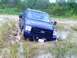 1989 Ford Bronco - A blue Ford truck is stuck in muddy terrain, with its front end partially submerged.