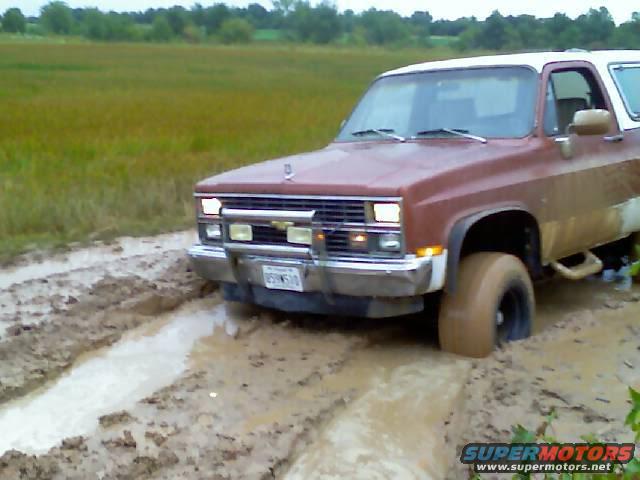 Brown and white SUV stuck in mud. License plate reads B5N510
