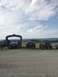 1989 Ford Bronco - Several lifted trucks and a blue SUV are parked in a gravel lot under a cloudy sky.