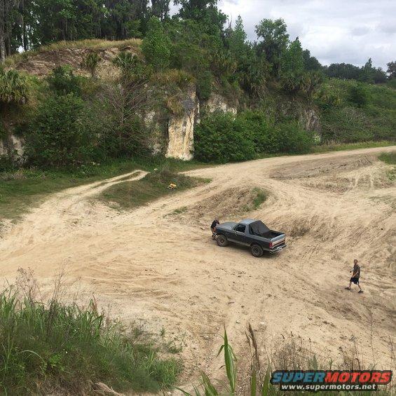 1989 Ford Bronco on a dirt track with a person walking nearby
