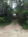 1989 Ford Bronco - A white van navigates a steep dirt path surrounded by dense trees and foliage.
