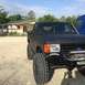 1989 Ford Bronco - A modified black Ford Bronco sits parked on a dirt lot, showing off its off-road capabilities.