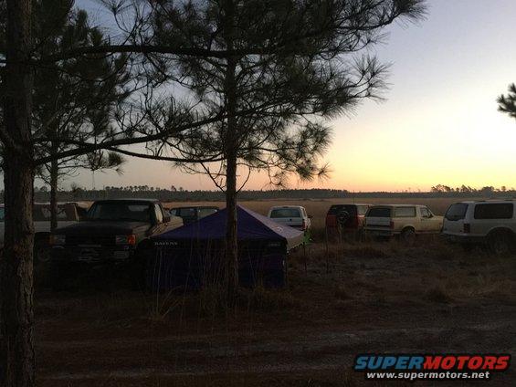 1989 Ford Bronco parked in a field with other vehicles at sunrise