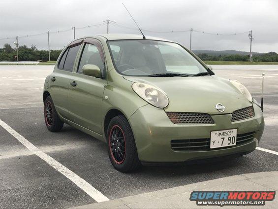 Green hatchback parked in a lot. It has a license plate with Japanese characters and numbers