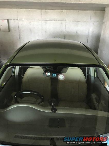Interior view of a car showing dashboard, steering wheel, and seats. A circular sticker with '29' is visible on the windshield