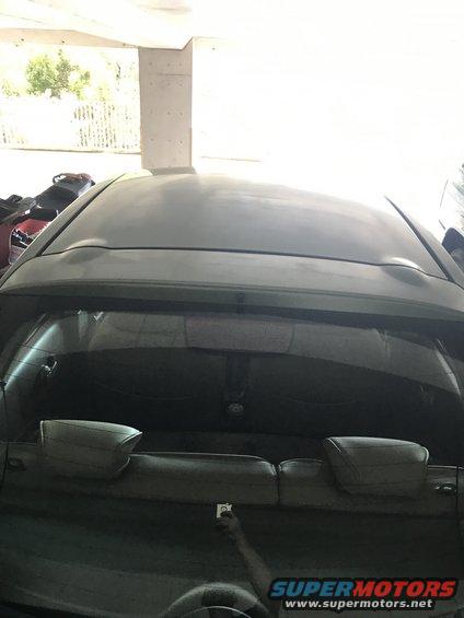 Rear view of a hatchback with a dented roof and a small sticker on the rear passenger door