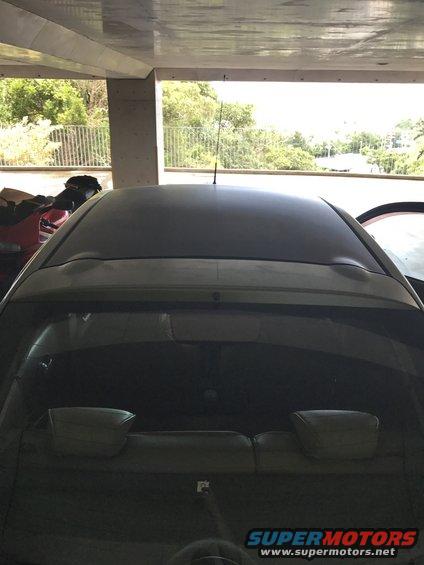 Dark-colored car's rear window and roof, seen from a low angle inside a parking structure