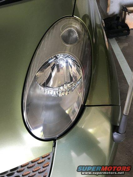 Green 2003 Nissan Micra headlight and fender, close-up front view