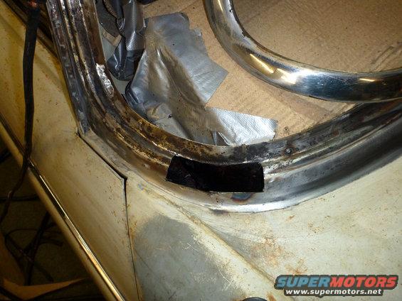 Close-up of a car's door frame with rust and a cut-out section, showing repair work. Some duct tape is visible