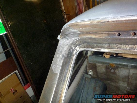 Close-up of car's A-pillar and roof seam undergoing repair, showing metalwork and primer