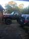 1989 Ford Bronco - A modified black Ford Bronco is parked beside a blue SUV in a driveway.