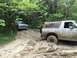 1989 Ford Bronco - Two Ford Broncos navigate a muddy trail, one deeply stuck in the mire.