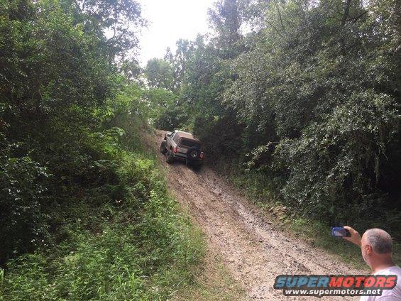 1989 Ford Bronco climbing a muddy hill, rear view