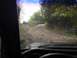 1989 Ford Bronco - Two SUVs navigate a challenging dirt trail, viewed from the perspective of another vehicle on the path.