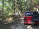1989 Ford Bronco - Two SUVs navigating a muddy trail through a wooded area.