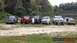 1989 Ford Bronco - A group of off-road vehicles, including a 1989 Ford Bronco, are lined up outdoors near a body of water.