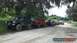 1989 Ford Bronco - Multiple off-road vehicles are parked in a line on a dirt path, with trees overhead.
