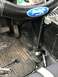 1989 Ford Bronco - The interior of a vehicle features a Ford-branded steering wheel and floor mat, with visible pedals and aftermarket wiring.