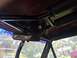 1989 Ford Bronco - A close-up of a vehicle's interior reveals a mounted fan and rearview mirror, with roll cage elements overhead.