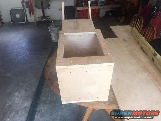 unfinished wooden box on table, with wood planks nearby