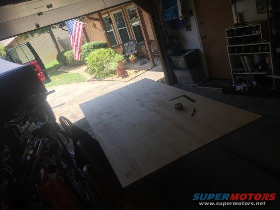 Garage interior with plywood sheet, tape measure, and speed square
