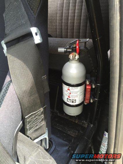 Fire extinguisher mounted behind the driver's seat, next to a seatbelt