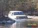 1989 Ford Bronco - A white 1989 Ford Bronco navigates through a muddy, water-filled wooded area.