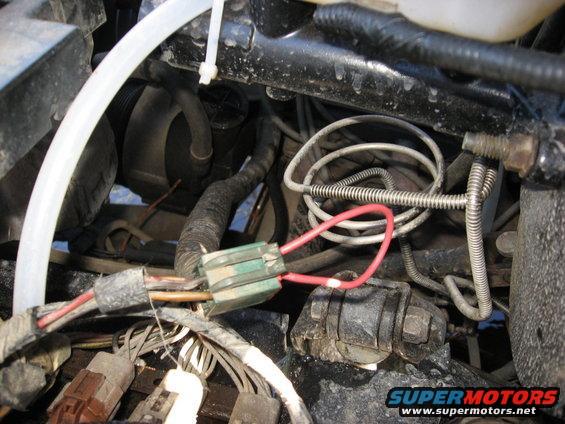 Close-up of engine wiring harness with a green fuse box and red wire