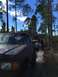 1989 Ford Bronco - Several vehicles are driving down a muddy, wooded path on a cloudy day.