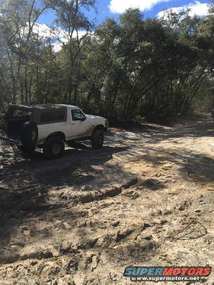 1989 Ford Bronco with aftermarket wheels and tires on a sandy trail