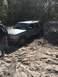 1989 Ford Bronco - A silver SUV, likely a Chevrolet Blazer from the late 1990s, is stuck in a sandy area with trees in the background.