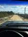 1989 Ford Bronco - View from inside a vehicle driving on a dirt road with another SUV ahead, surrounded by trees and brush.