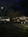 1989 Ford Bronco - A lifted Ford Bronco is transported on a trailer behind a pickup truck at night.